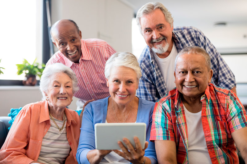 group-of-seniors-smiling-and-looking-at-tablet-web